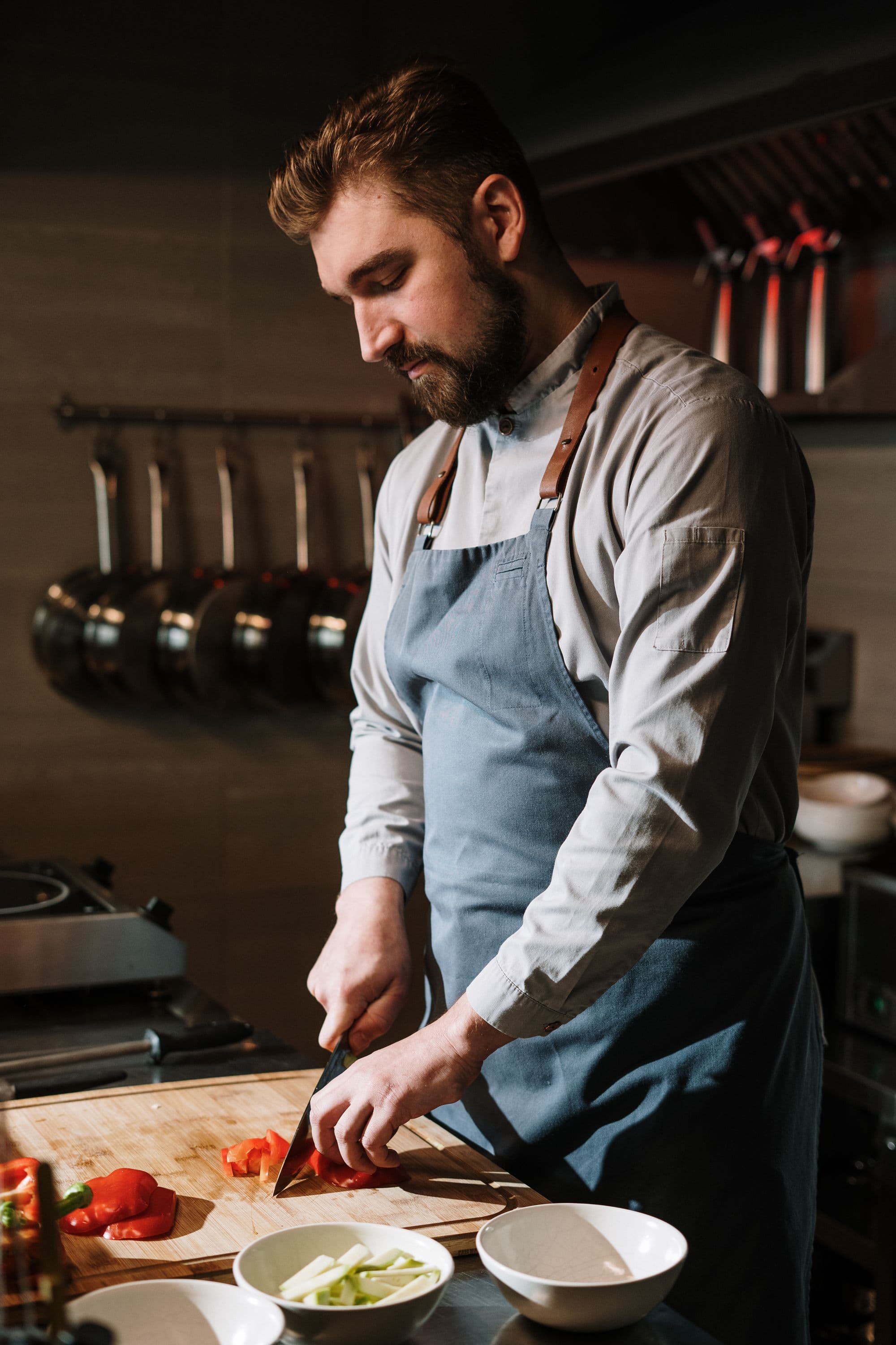 A chef using a kitchen knife at a wooden board